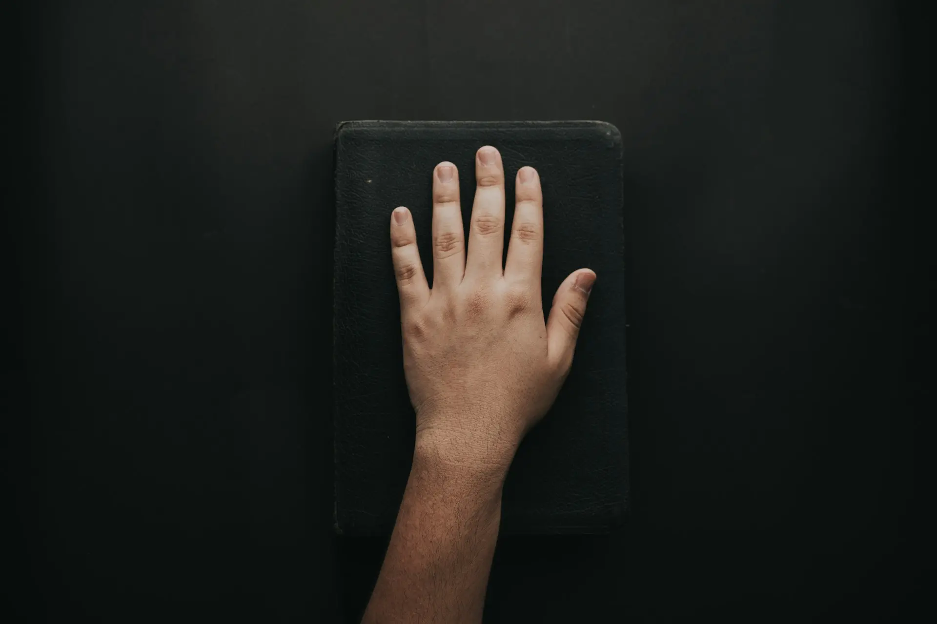 left human hand on black book